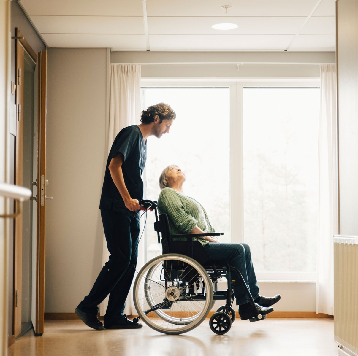 Male nurse pushing wheelchair with patient